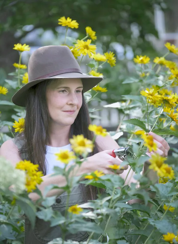 A garden designer in a sun hat among yellow daisies