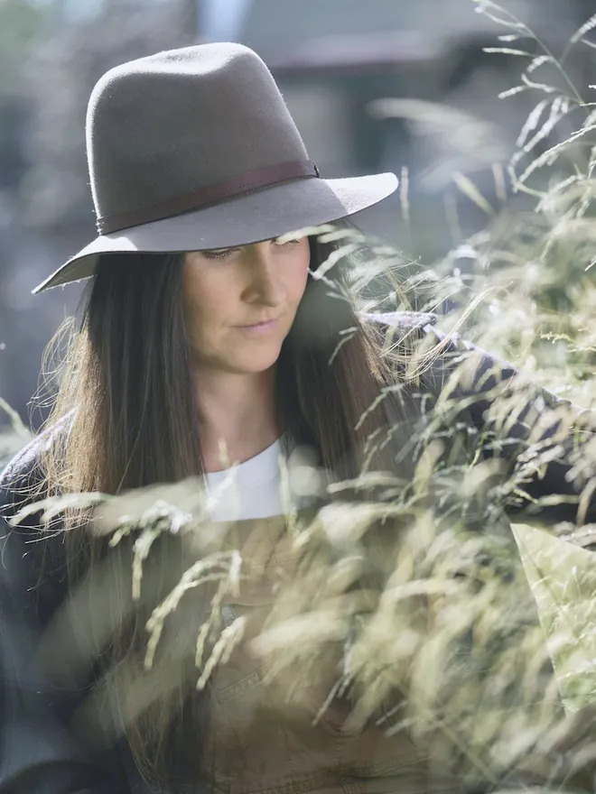 The designer among tall grasses in a sun hat